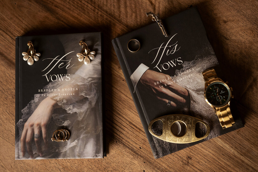 Close-up of a couple holding hands over their personalized vow books