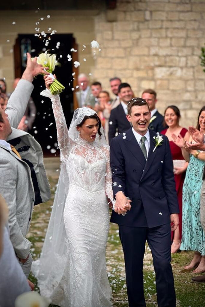Newlyweds celebrating with guests outside a stone wedding venue