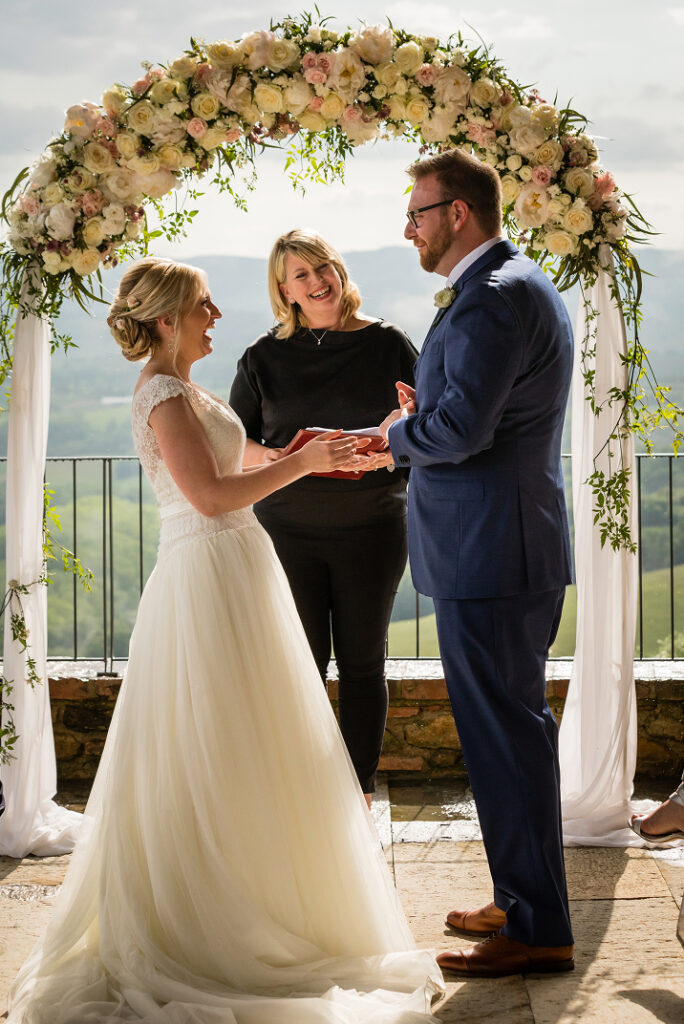 Couple exchanging vows with their officiant at an outdoor wedding ceremony