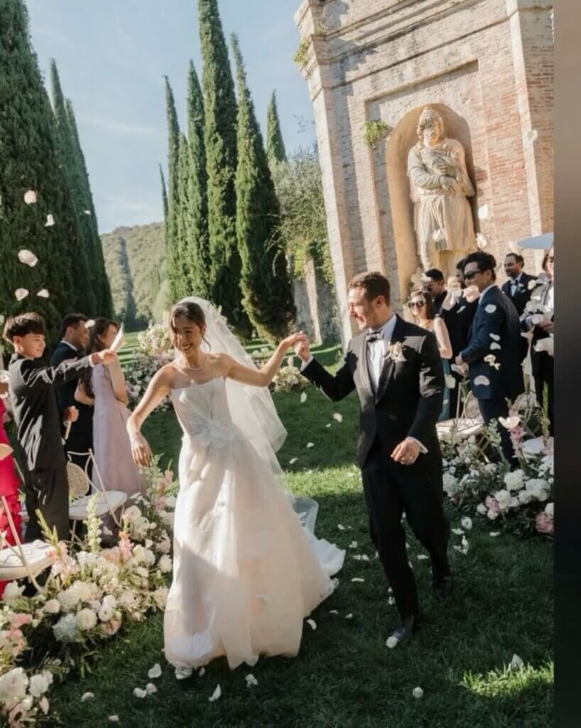 Newlyweds walking through flower petals after their outdoor wedding ceremony